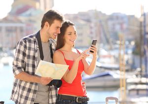 Young couple on holiday using phone and map