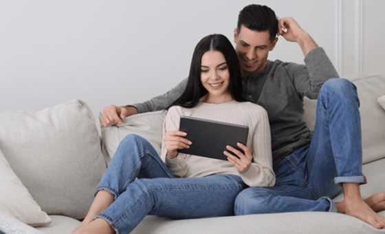 Couple using home internet on couch.