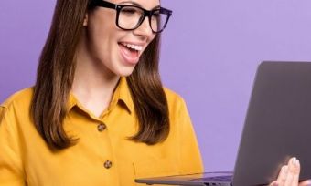 A woman looking at a laptop excitedly