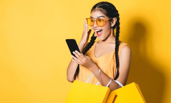 Young woman in yellow using mobile phone against yellow background