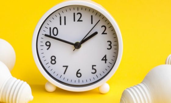 Clock on yellow background with light bulbs