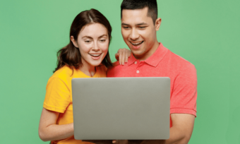 young couple happy using laptop with green background