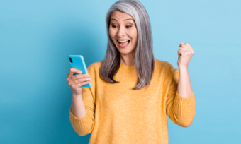 Happy older woman using phone with blue background