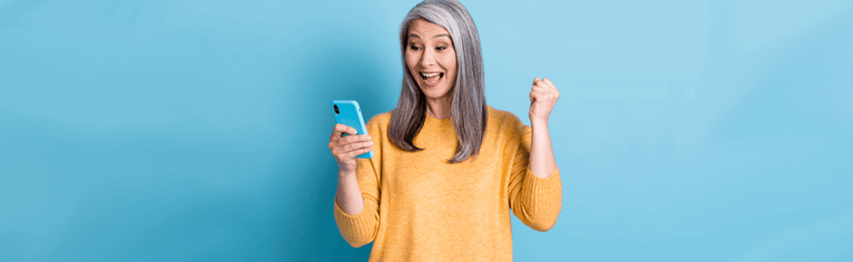 Happy older woman using phone with blue background