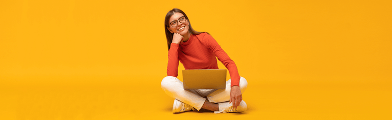 Young woman using laptop against orange background.