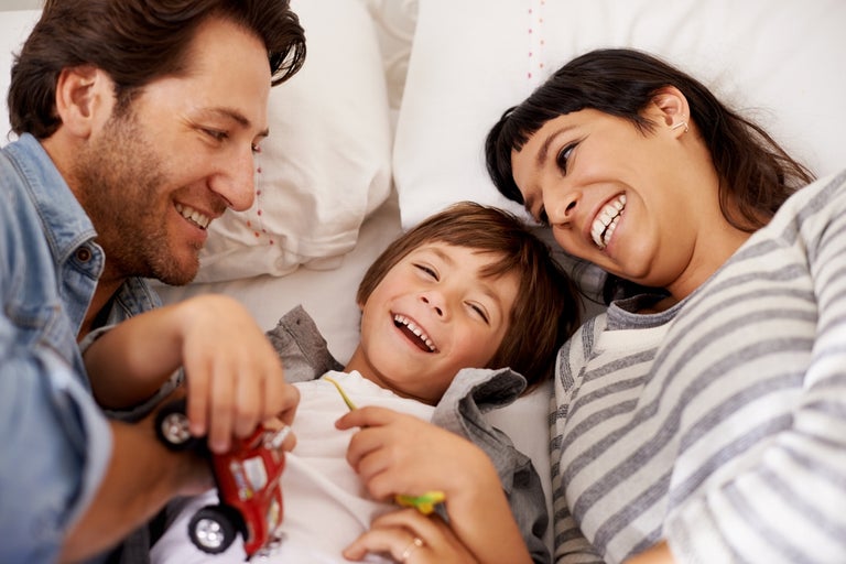 Mother and father and young child laughing and playing with toys