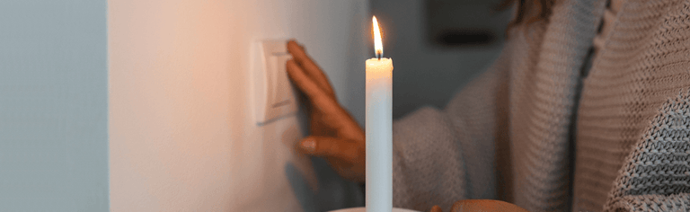 Power outage in home, woman with lit candle checking light switch