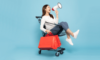 Black Friday sale - woman with shopping bag in trolley and megaphone